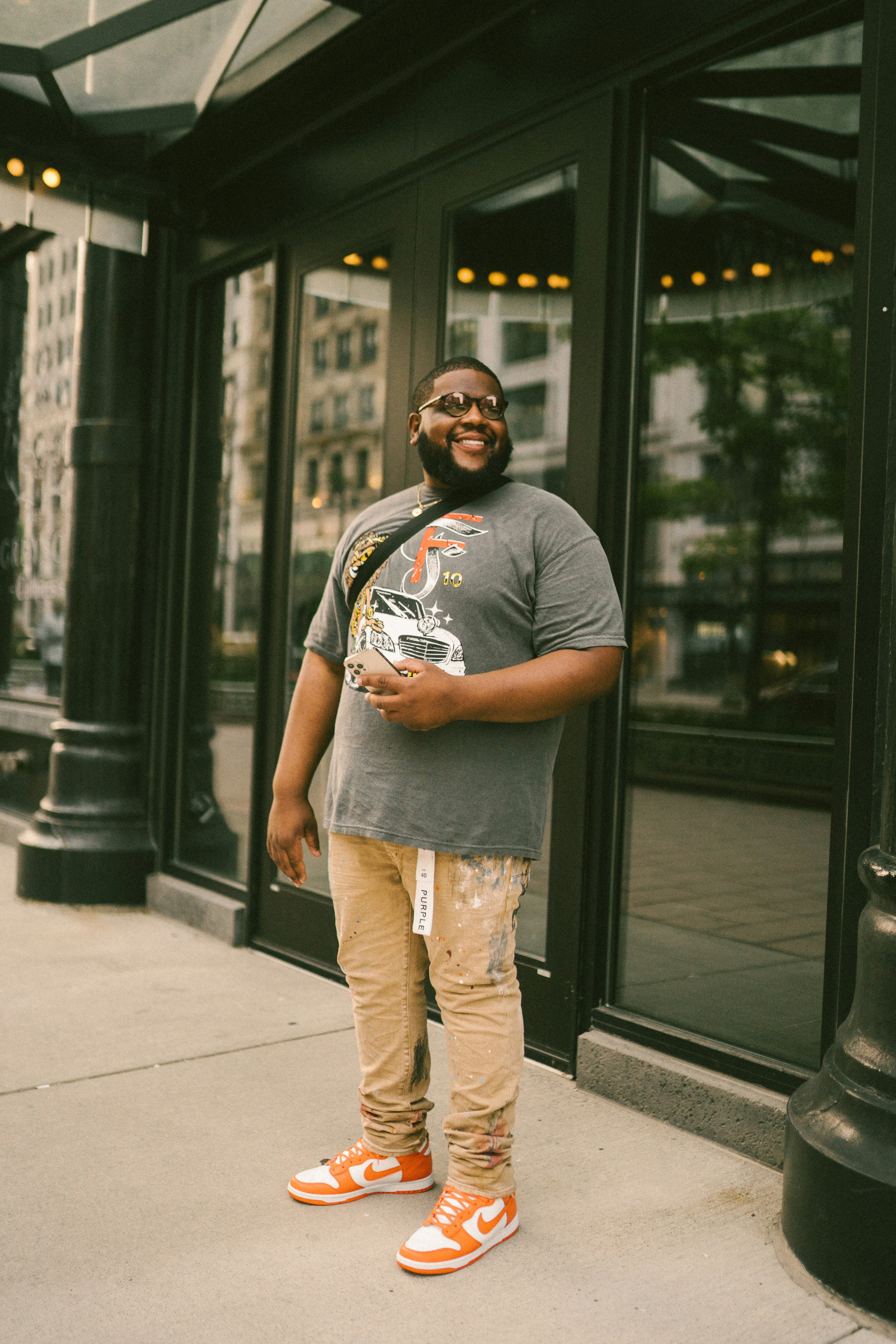 man in gray crew neck t-shirt and brown pants standing on sidewalk during daytime